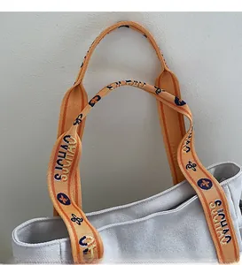 Close-up of contrast orange woven handles with blue patterns on light gray canvas tote bag