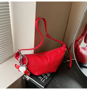 Close-up of a red pleated dumpling bag with lychee grain texture and knot strap