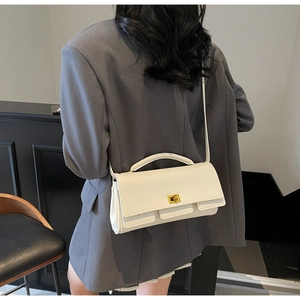 Detail view of cream rectangle bag with gold clasp shown on a grey blazer outfit