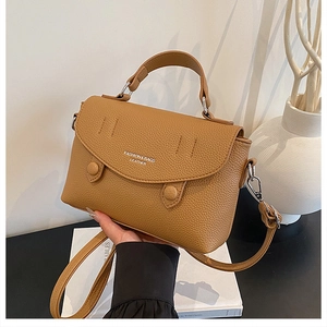 Close-up of caramel leather handbag featuring fine litchi grain and silver hardware