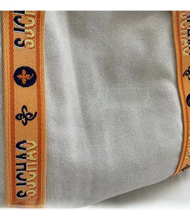 Close-up of lightweight canvas fabric texture with orange woven straps on a tote bag