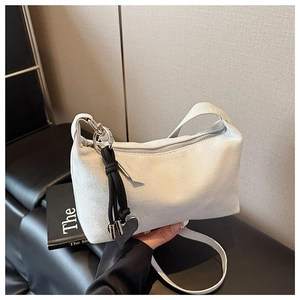 Detail of white suede pillow bag featuring silver hardware and heart rope pendant decoration