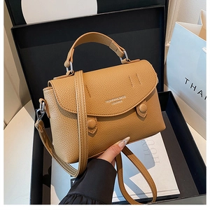 Detail of tan pebble leather handbag with silver logo lettering in a luxury gift box