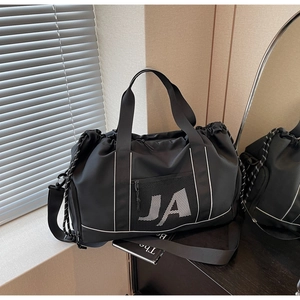 Detailansicht der schwarzen Nylon-Reisetasche mit JA-Logo und Netztasche auf dem Tisch