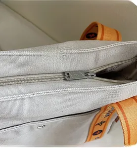 Detail of smooth metal zipper closure on beige canvas tote with woven patterned strap