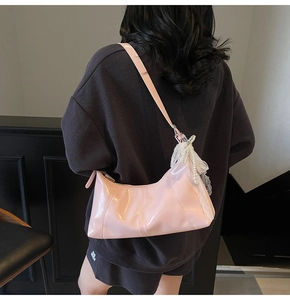 Close-up of pink patent leather hobo bag with white lace bow and pearl decoration