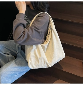 Detailed shot of large beige tote bag with pleated texture on a wooden staircase
