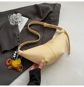 Detail of creamy yellow crescent shoulder bag with litchi texture and elephant charm