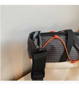 Detail of durable black swivel hook and orange elastic cord on grey grid fabric bag