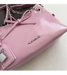 Close-up of pink leather tote bag featuring a leather bow, silver chain, and clear k logo