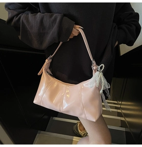 Detail of pink patent leather shoulder bag with pearl bow and lace charm accessory