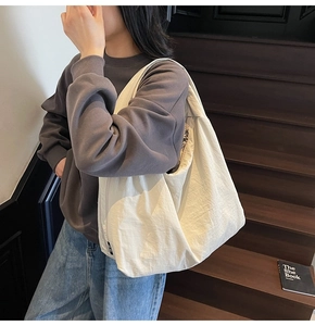 Detail of cream white oversized tote bag showing lightweight nylon texture and small black tag