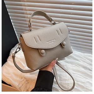 Close-up of greige lychee pattern leather handbag with silver hardware and logo detail