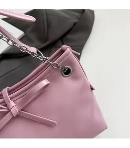 Detail view of pink leather tote bag featuring a decorative bow and silver chain strap