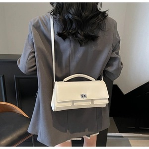 Detail of silver twist lock closure on cream minimalist commuter crossbody baguette bag