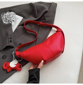 Detail of red crescent bag with pebble leather texture and cute elephant charm accent