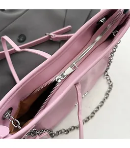Close-up of smooth silver zipper and metal chain strap on a pink leather tote bag