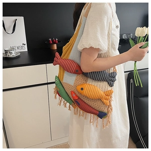 Detail of a beige knit shoulder bag with colorful plush fish and long fringe tassels