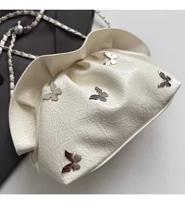 Detail of cream white pleated cloud bag with silver butterfly charms and chain strap