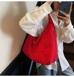 Detail view of the red nylon tote bag featuring a side vertical zipper and wide strap