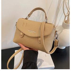 Detail of khaki leather handbag featuring embossed lettering and adjustable strap