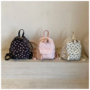Detailed close-up of mini backpacks with textured jacquard and delicate bow patterns