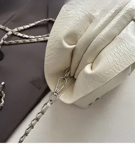 Close-up of white pleated bucket bag featuring shiny texture and silver chain strap detail