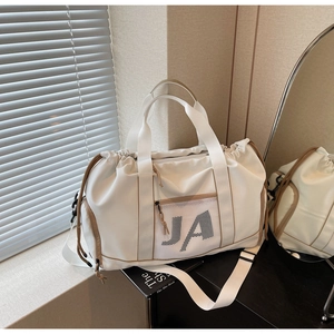 Detail einer cremefarbenen Nylontasche mit braunem Rand und verstellbarem Gurt