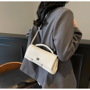 Chic cream white baguette bag shown as a shoulder style on a model with grey blazer