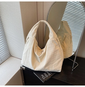Close-up of cream white hobo bag with side zipper and modern wrinkled nylon texture