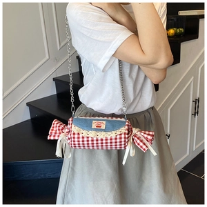 Detail of candy-shaped checkered handbag with blue denim flap and cherry patch