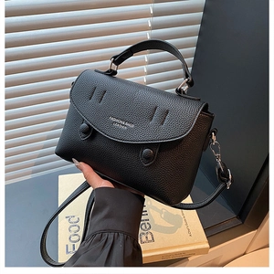 Detail of black lychee grain leather crossbody bag with fashion text and round buckles