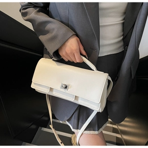 Close-up of white leather baguette bag featuring silver metal turn-lock and layered flap detail