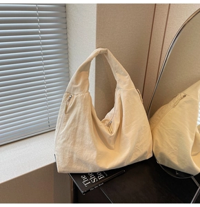 Detail view of large cream tote bag showing crinkled texture and side zipper pocket