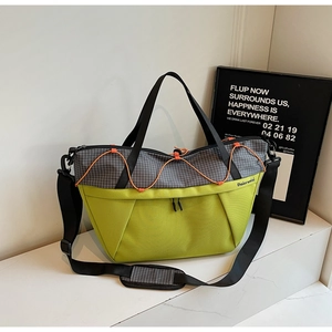 Detail of multi-functional green and plaid bag featuring orange drawstrings and logo