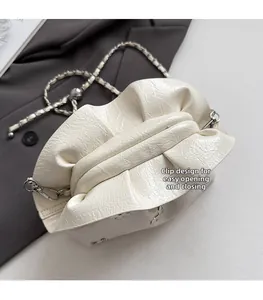 Detail of off-white pleated bucket bag with metallic chain and easy clasp closure