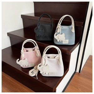 Detailed view of woven bucket bags in multiple colors with cute elephant pendants