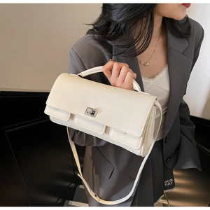 Detail view of cream white square handbag featuring silver metal lock and leather strap