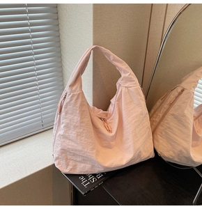 Detailed close-up of pink pleated nylon tote bag with functional zipper pockets