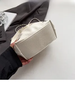 Detailed close-up of the smooth flat base and pleated texture of the beige bucket bag