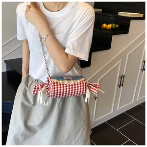 Detail of candy-shaped plaid crossbody bag with lace trim and blue denim patchwork