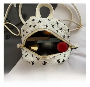 Mini white backpack with bubble texture and bow print showing internal storage capacity