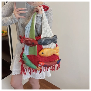 Detail of colorful knitted tote bag with decorative fish charms and red fringe tassels