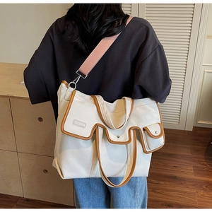 Détail du sac cabas en toile avec bordure en cuir marron et large bandoulière rose