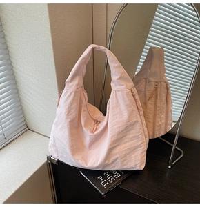 Detail shot of pink hobo tote bag showing nylon texture and multiple zipper pockets