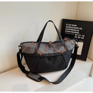 Detail of grid patterned crossbody bag with orange elastic cord and adjustable strap