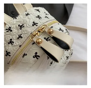Detail showing high-quality gold dual zippers and black bow print on white bubble fabric