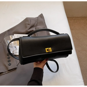 Close-up of black leather handbag with a golden square lock and elegant top handle detail