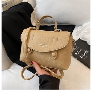 Close-up detail of beige litchi grain texture bag with top handle and fashion logo