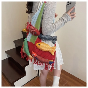 Detail of red hollow knit beach tote bag featuring colorful fish charms and fringe trim